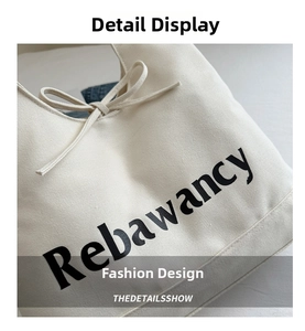 Detailopname van beige canvas draagtas met Rebawancy-tekst en decoratieve strik
