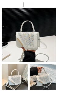 Close-up of white square handbag with colorful tweed flap and gold metal bar detail