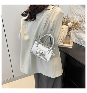 Silver metallic mini tote bag with bow detail and heart stitching worn by model
