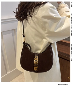 Sac selle en daim marron avec logo en métal doré et fine bandoulière en cuir sur modèle