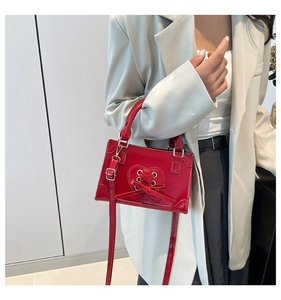 Detail of red leather bag featuring a unique heart-shaped lace-up design with metal eyelets