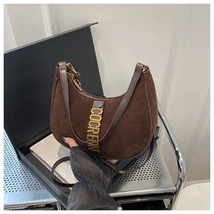 Détail du lettrage doré sur sac demi-lune en daim marron avec bandoulières cuir