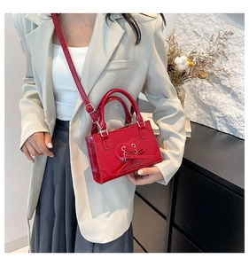Detail of red heart cutout shoulder bag featuring lace-up straps and polished silver hardware