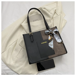 Detail of color-block tote bag with a decorative silk scarf and smartphone for scale