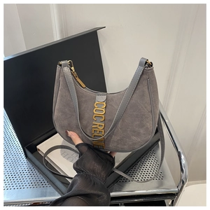 Vue détaillée du sac en daim gris avec lettres métalliques dorées et fermeture éclair