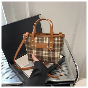 Dettaglio della borsa tote vintage a quadri con manici in pelle e tracolla regolabile