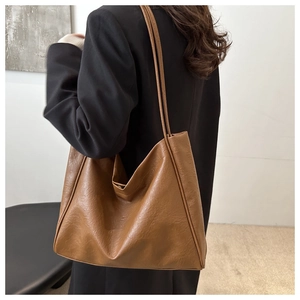 Sac cabas en similicuir marron porté à l'épaule, montrant sa grande taille et texture