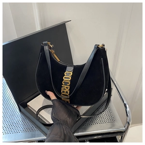 Détail du sac hobo en daim noir avec lettres métalliques dorées en gros plan