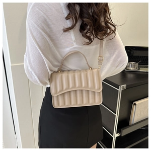 Detailansicht der beige plissierten Umhängetasche mit Metallschnalle und Schultergurt