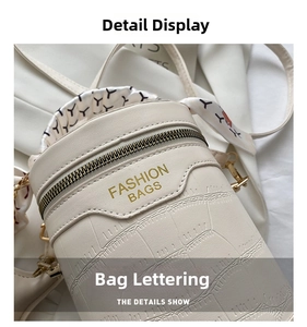 Detail of cream crocodile embossed cylinder bag with gold logo and silk scarf handle