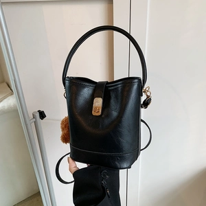 Vintage textured black bucket bag with golden twist lock and brown faux fur pompom