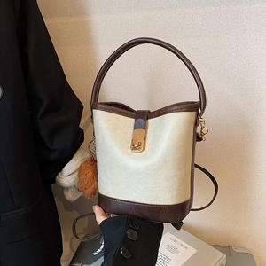 Chic two-tone bucket bag in cream and brown leather with bear charm and golden buckle