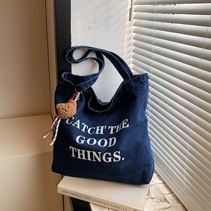 Denim tote bag with 'CATCH THE GOOD THINGS' print and brown bear plush charm