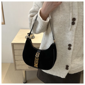 Détail du logo doré COCREONE sur un sac à main en daim noir porté par un modèle