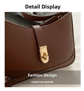 Close-up of caramel leather underarm bag featuring a polished gold-tone metal twist lock