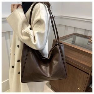 Grand sac cabas en cuir marron foncé avec de longues bandoulières sur un manteau beige