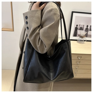 Vue latérale d'un grand sac fourre-tout noir minimaliste avec de longues lanières