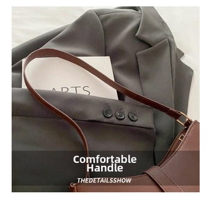 Detail of fine stitching and metal buckle on brown leather underarm bag with sleek handle
