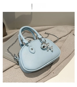 Détail du sac bleu ciel en cuir grainé avec charm chien ballon et chaîne argentée