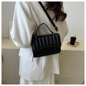 Detailansicht einer schwarzen Stepptasche getragen von einem Model in modernem Raum