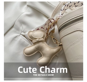 Detail of white crocodile-pattern bucket bag with dog charm and red silk scarf handle