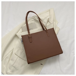 Detail of brown tote bag with adjustable metal buckle on a cream blazer