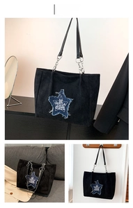 Detail of black tote bag with blue star patch, corduroy texture and metal chain strap