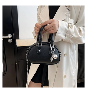 Détail du sac Boston en cuir noir avec chaîne argentée et breloque chien ballon