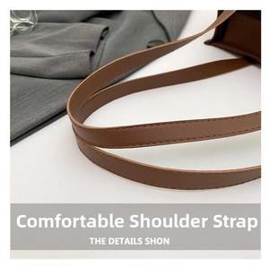 Close-up of textured brown leather shoulder strap with neat stitching on a tote bag
