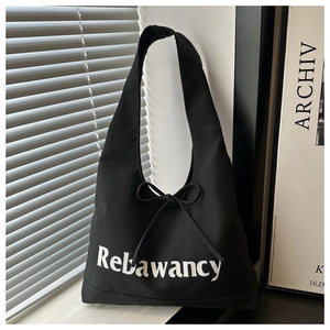 Detail van zwarte canvas shopper met witte letters en een decoratieve strik als detail
