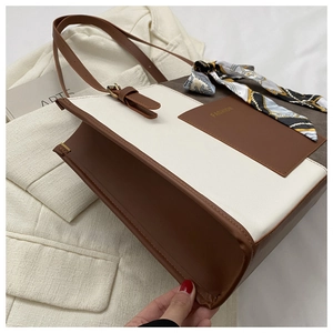 Detail of color-block tote bag with leather texture, fashion logo and silk scarf handle