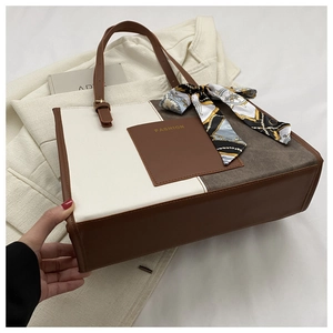 Detailed shot of canvas and brown leather tote featuring a silk scarf and fashion text