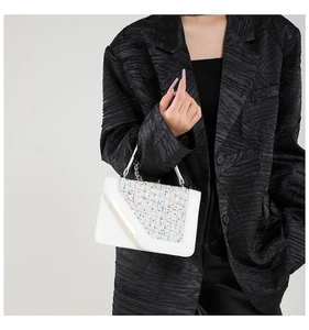 White leather handbag with colorful tweed flap detail and gold trim held by model