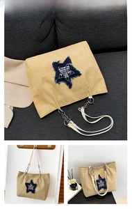 Detail of khaki canvas tote with blue star patch and metal chain shoulder strap