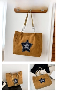 Detail of a brown suede tote bag featuring a denim star patch and metal chain strap