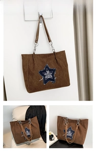 Detail of coffee brown corduroy tote bag with denim star patch and metal chain strap