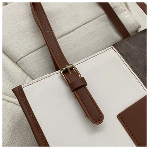 Detail of adjustable brown leather shoulder strap with antique bronze buckle on tote bag