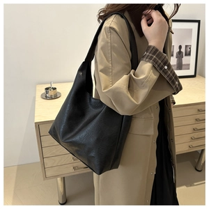 Detailed view of a soft black leather oversized hobo bag on a model shoulder