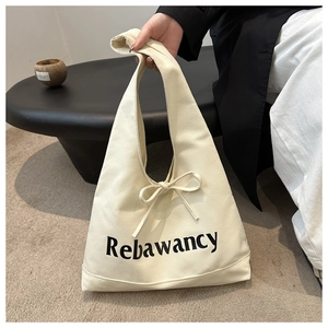 Detail of off-white canvas tote bag with black letter print and chic bow decoration