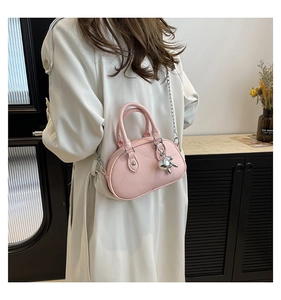Détail du sac à main rose en cuir grainé avec breloque lapin argentée et bandoulière