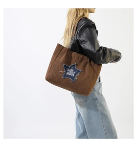 Detail of suede tote bag featuring a denim star patch and elegant metal chain strap