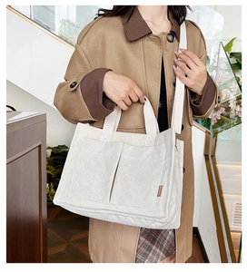 Close-up of white corduroy tote bag showing vertical ribbed texture and fashion label