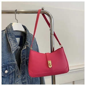 Close-up of a stylish rose pink shoulder bag with a gold metal clasp on a metal stand