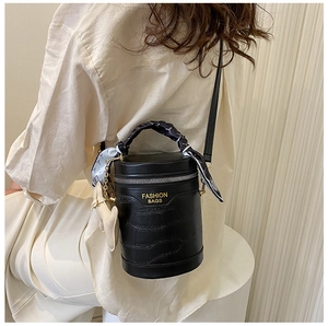 Detail of a black crocodile pattern cylinder bag with fashion silk scarf handle