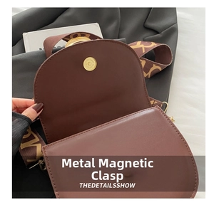 Close-up of vintage metal magnetic clasp on brown leather saddle bag with wide strap