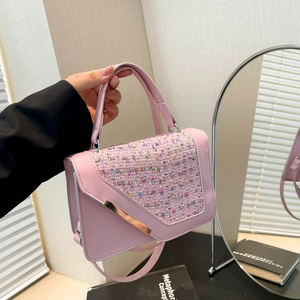 Pink square handbag with rainbow tweed flap and gold metal buckle held in hand