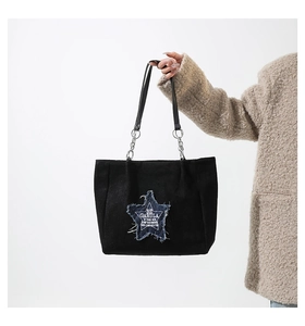 Detail of star patch with frayed edges and logo on black canvas tote shoulder bag