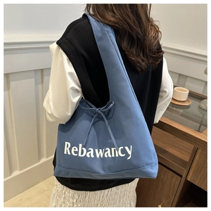 Detail of blue canvas tote bag featuring white artistic lettering and elegant bow strap knots