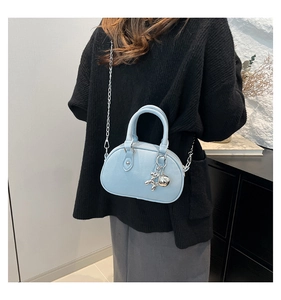Détail du sac à main bleu clair en cuir texturé avec chaîne et breloque chien ballon