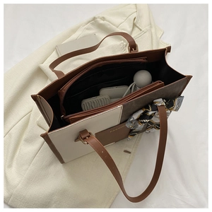 Detailed interior of color-block tote bag showing zipper pocket and scarf accessory